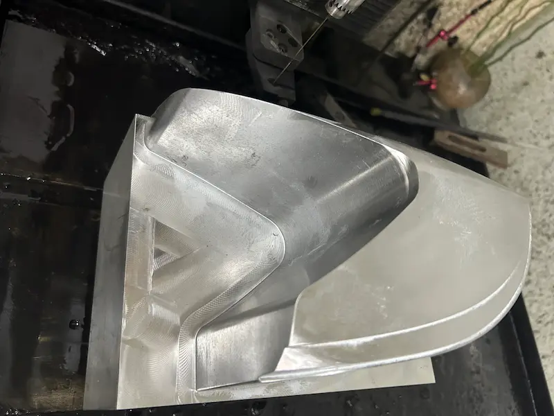 Close-up of polished mold steel surface showing orange peel texture and pitting defects during mold finishing inspection