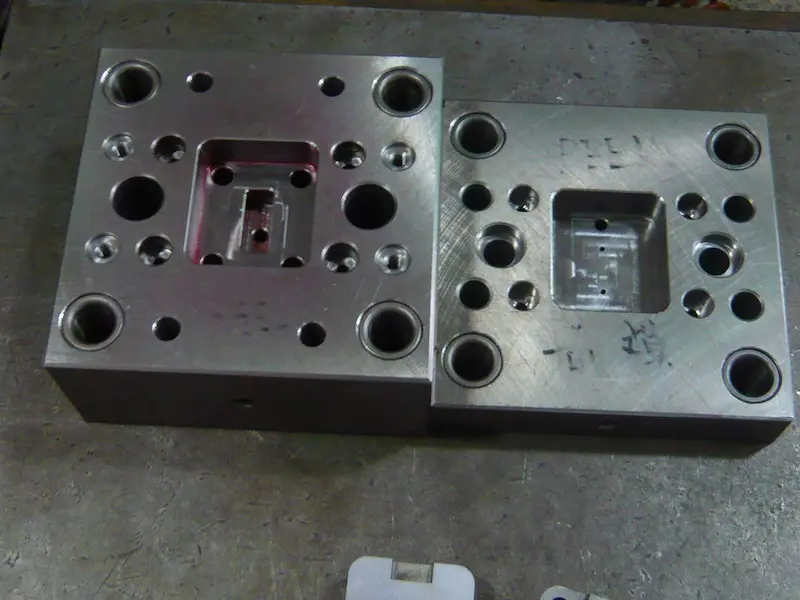 Close-up of an injection molded plastic part showing gate blush, radial flow streaks, and surface discoloration around the point gate.